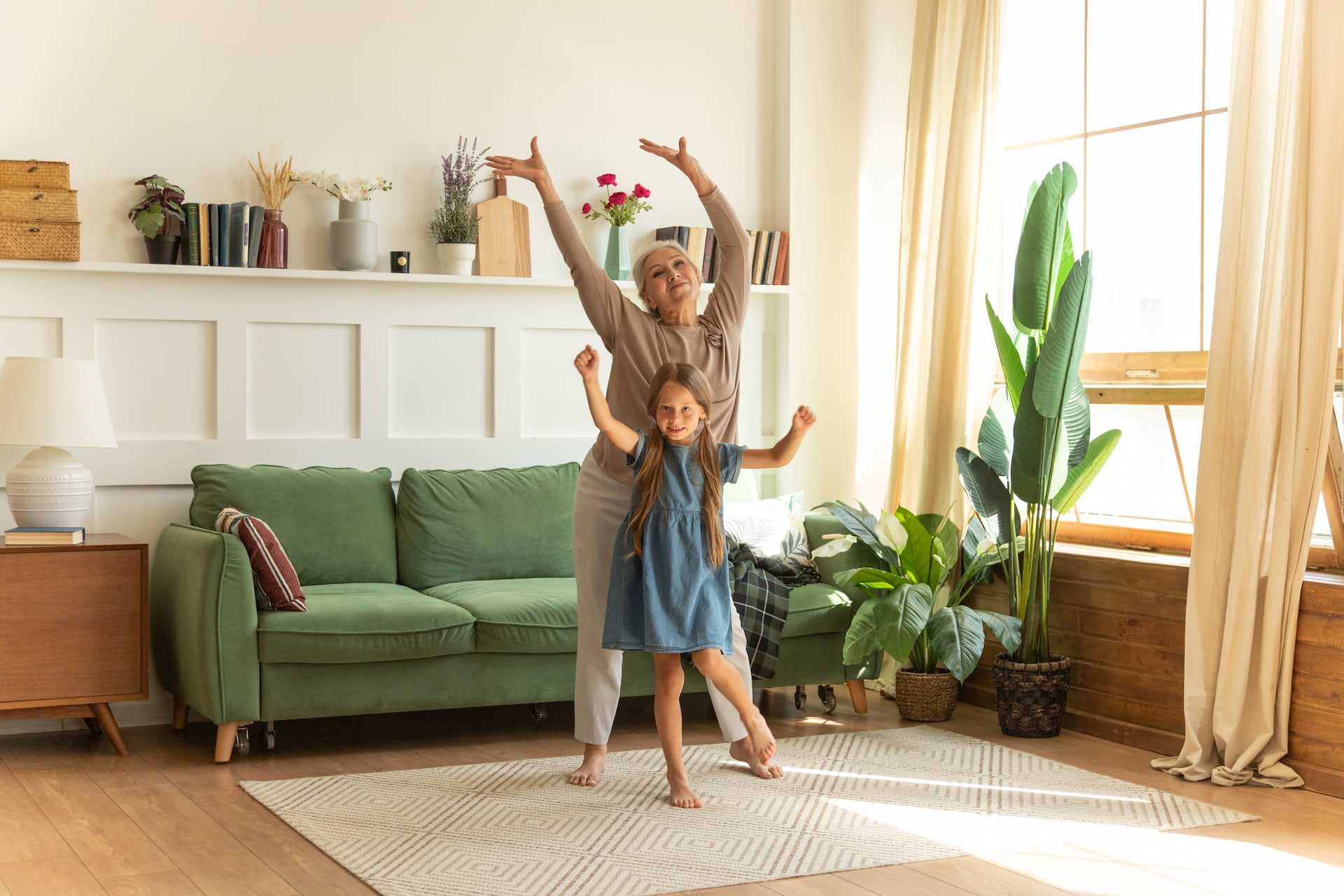 Photo of an elderly lady and a young girl dancing together in a front room.