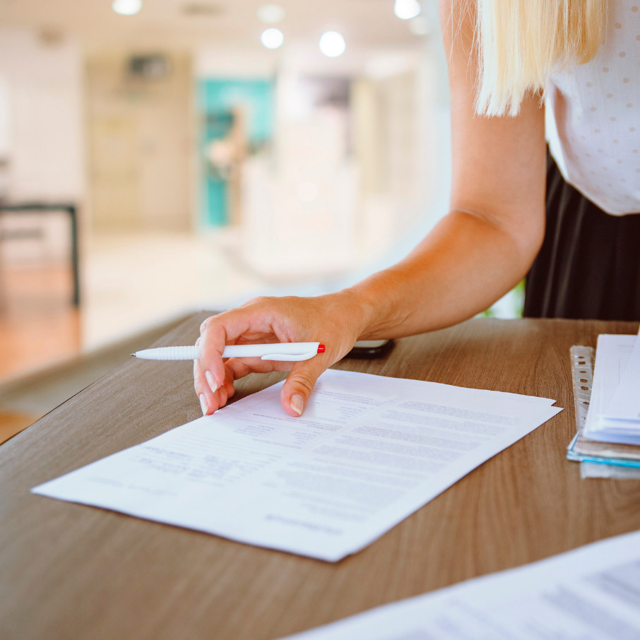 An insurance broker sat at a desk, holding a pen and a village hall risk assessment document.